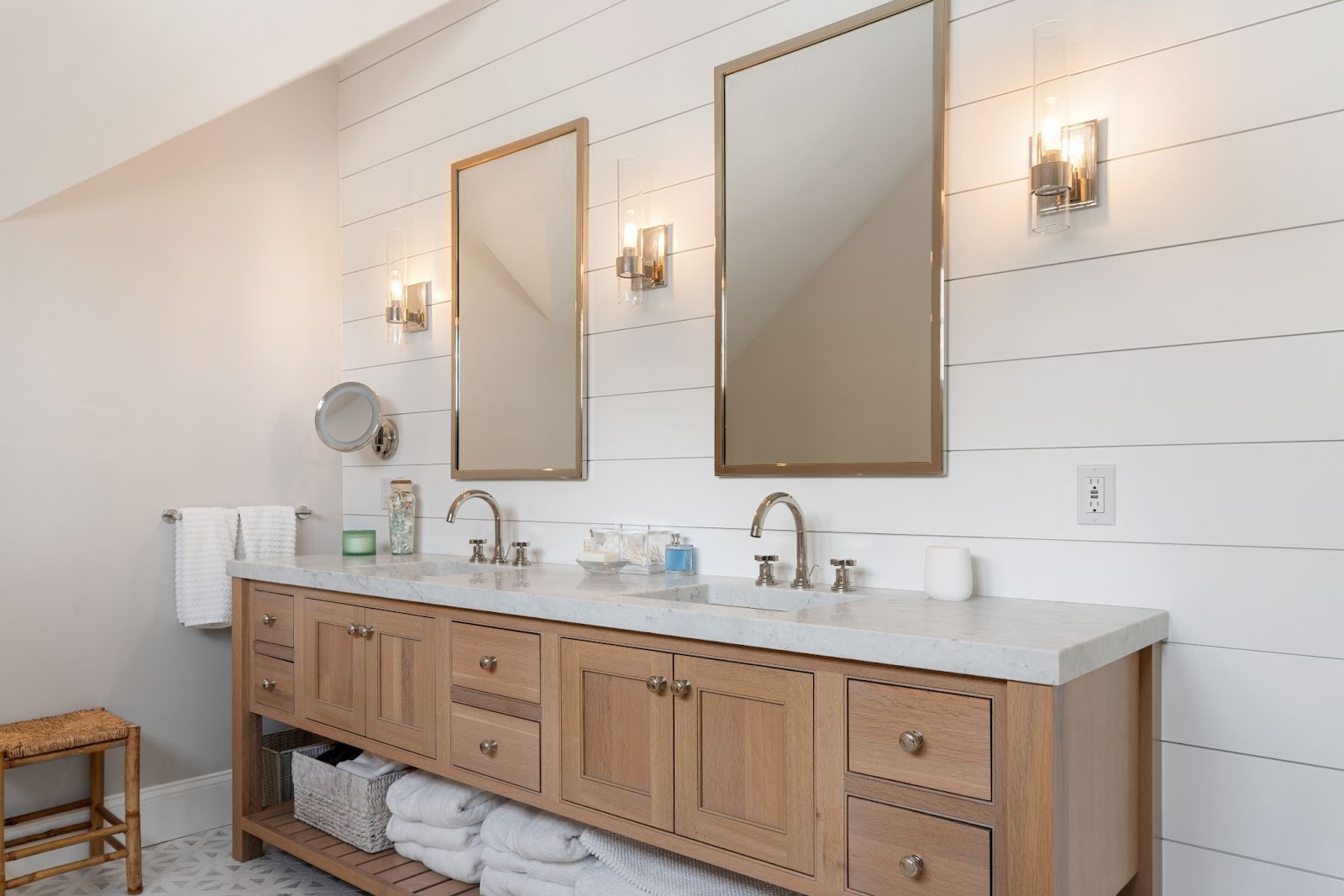 The picture depicts a sleek, white bathroom with two “vessel-style” sinks and 2 vertical mirrors.