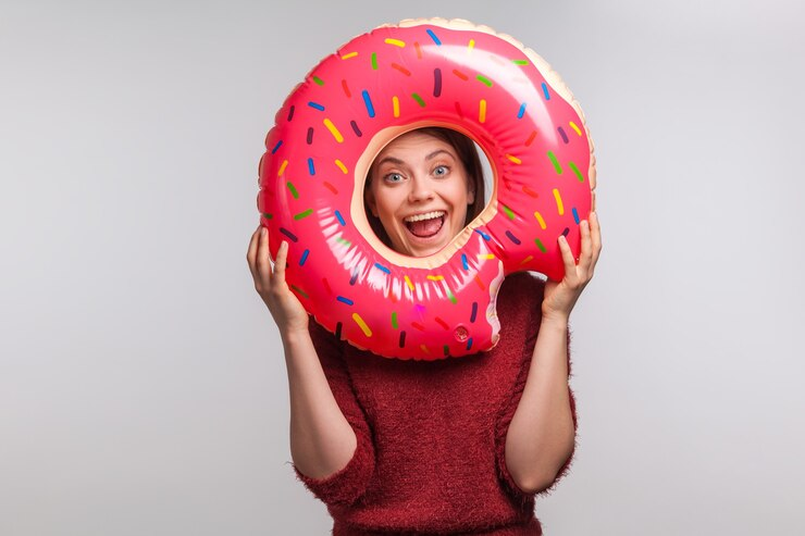A Girl Posing Funny With A Donut In Front of Her Face