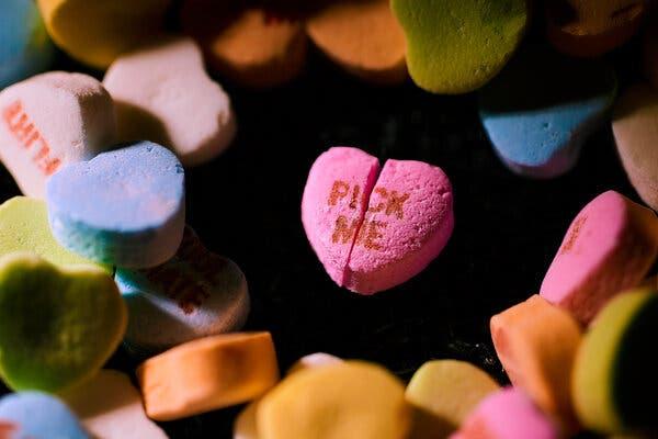 A closeup of a pink candy heart that reads "Pick Me" and that is split in half.