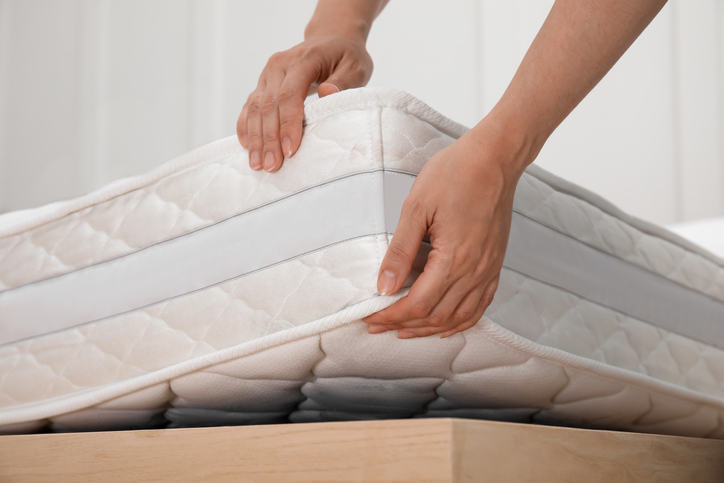 Man picking up a corner of the mattress to prepare for storage.