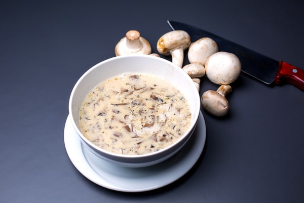 Creamy sauce on a bowl with whole mushrooms on the side