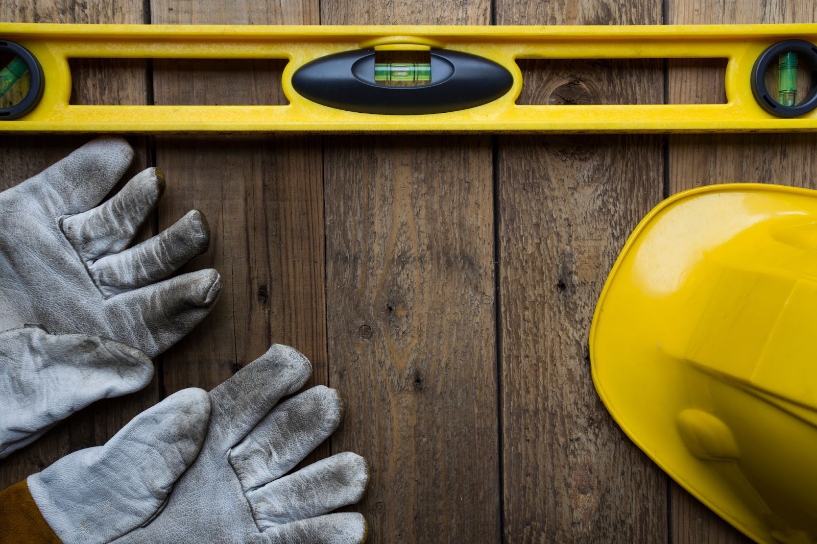 Gloves, level, and hard hat on top of a ground level deck. 