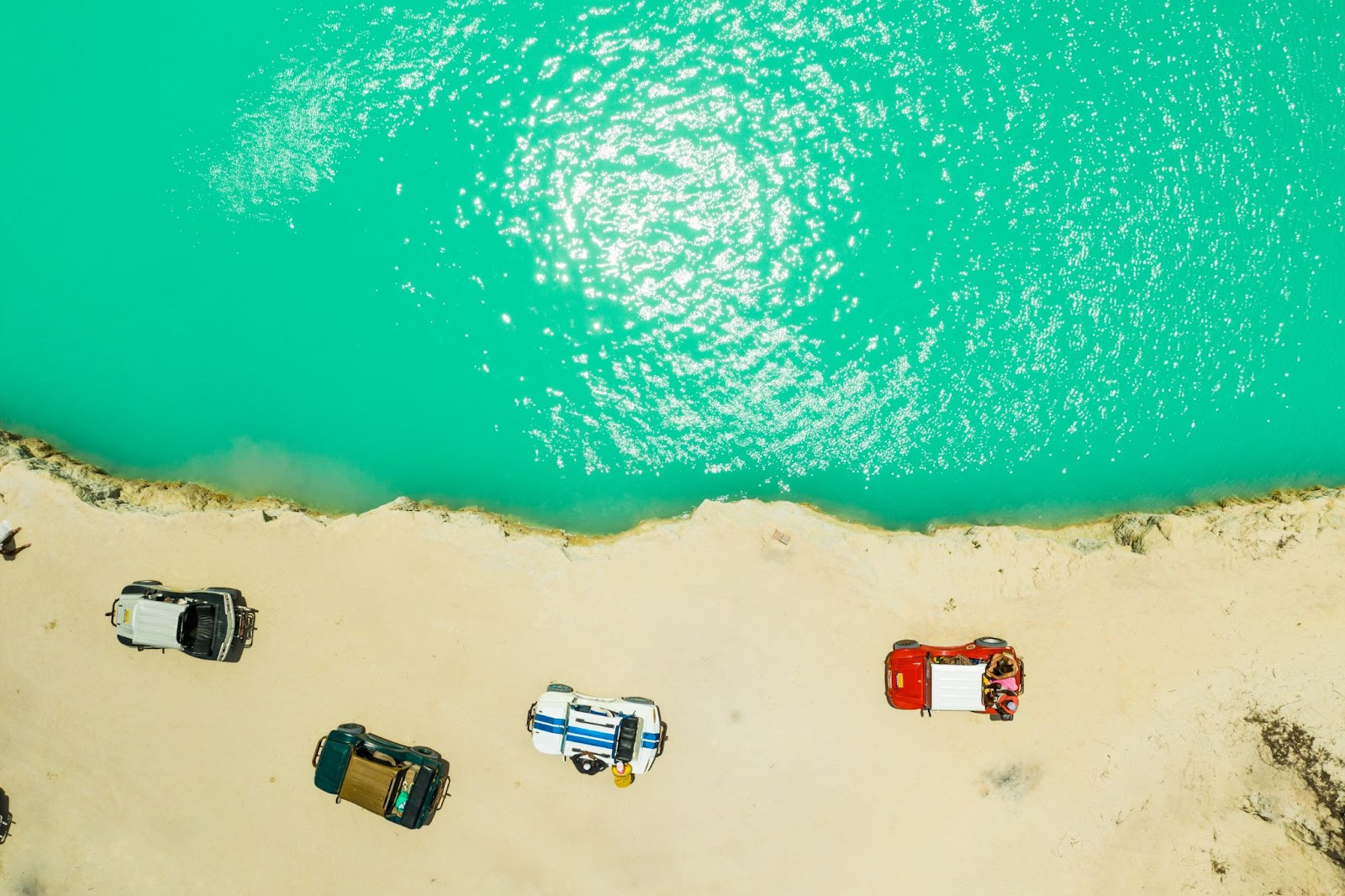 Vista de cima do Buraco azul, em Jericoacoara, com jipes coloridos percorrendo a orla do lugar