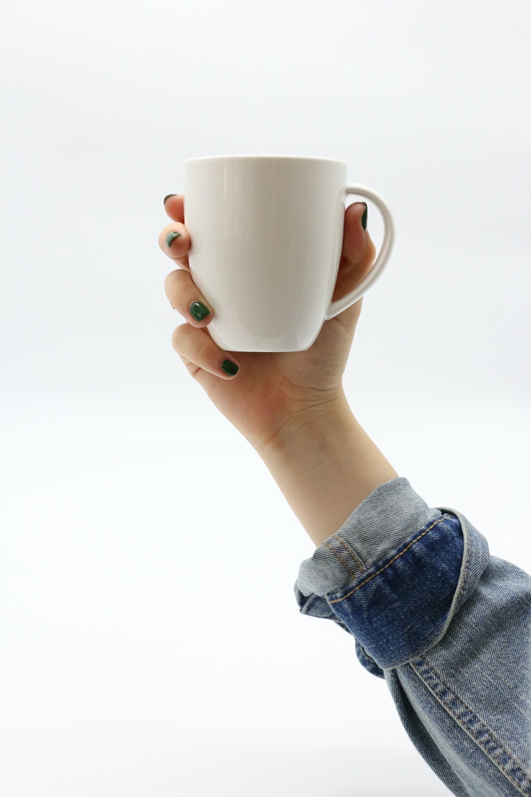 A Person's hand holding a cup with white coffee on a white background.