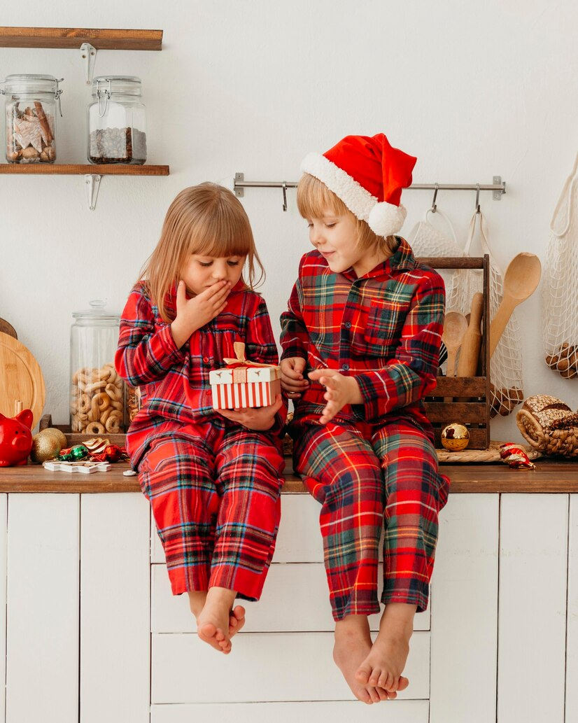 Cute siblings in red pajamas enjoying Christmas together.