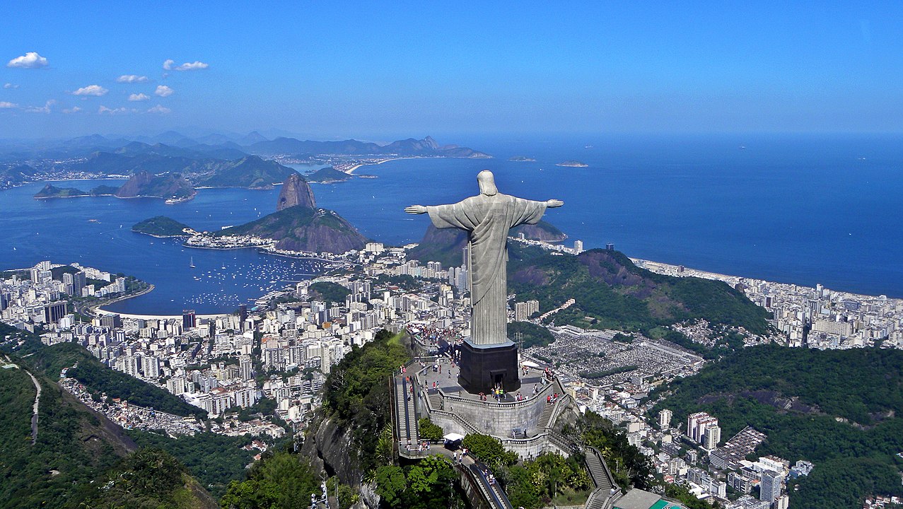 A panoramic view of the statue at the top of Corcovado Mountain with Sugarloaf Mountain (centre) and Guanabara Bay in the background.