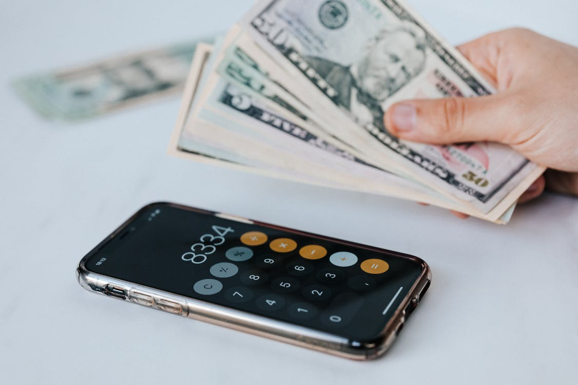 A person holding cash with a calculator