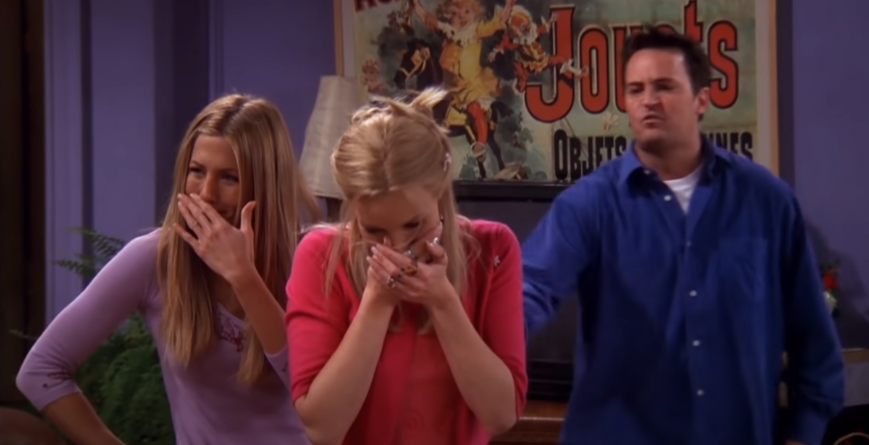 Phoebe and Rachel laughing at Chandler in a scene from the sitcom FRIENDS