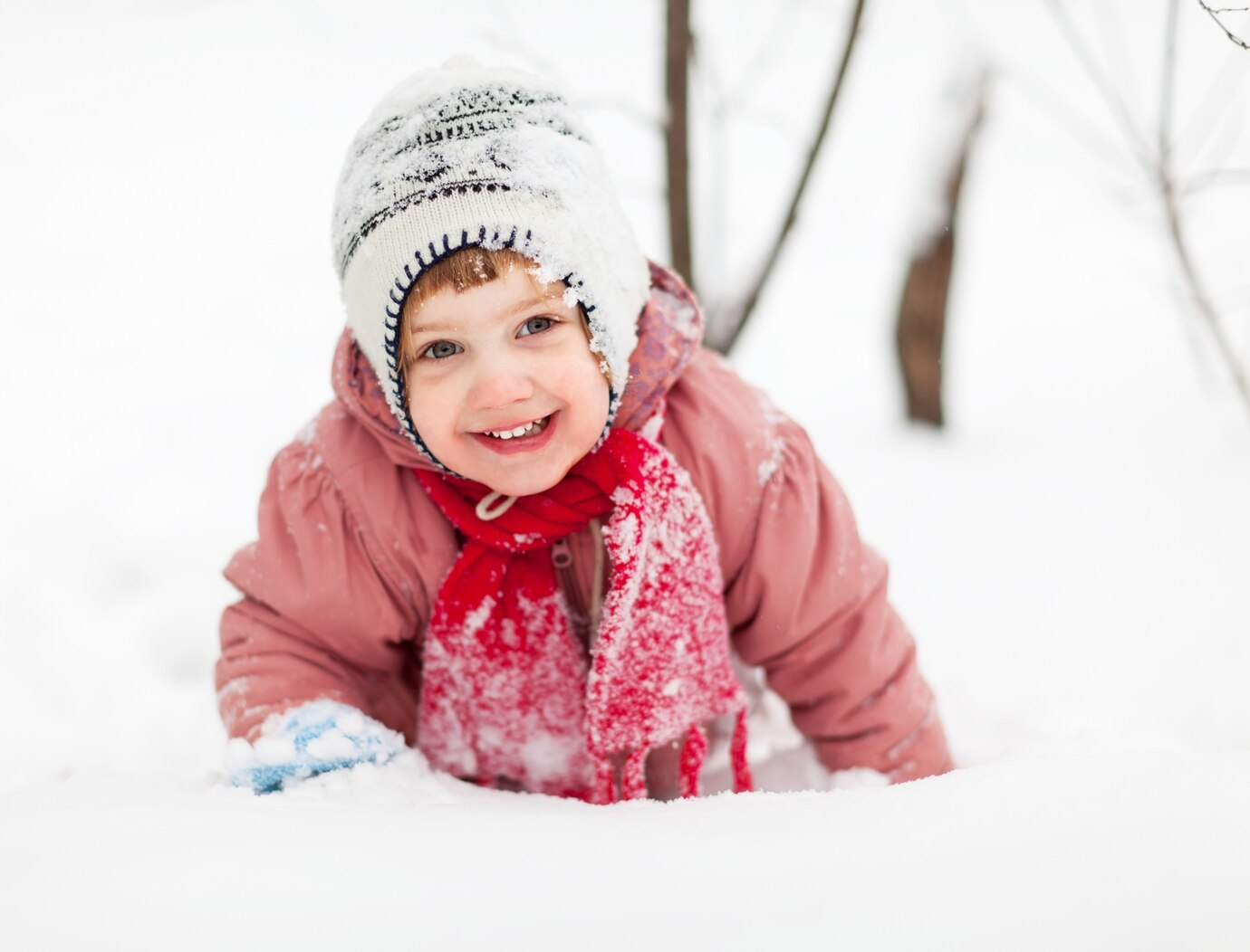 A cute child in the snow laughing joyfully.