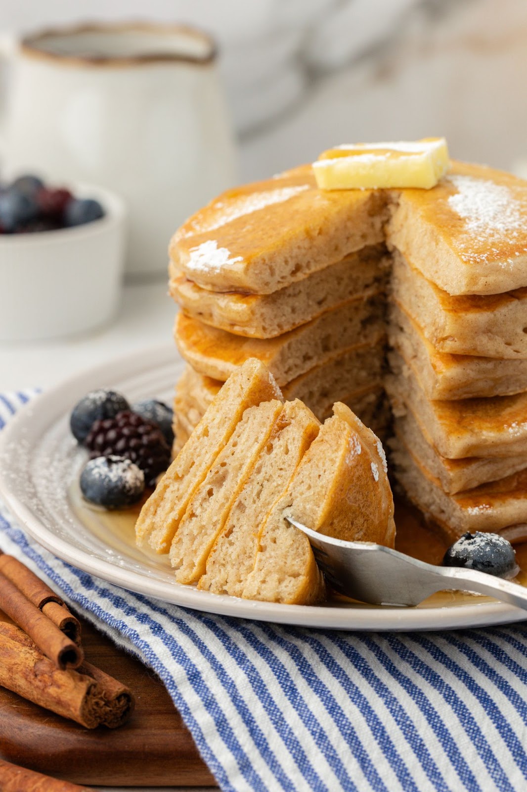 stack of pancakes with a bite missing on a plate with a fork