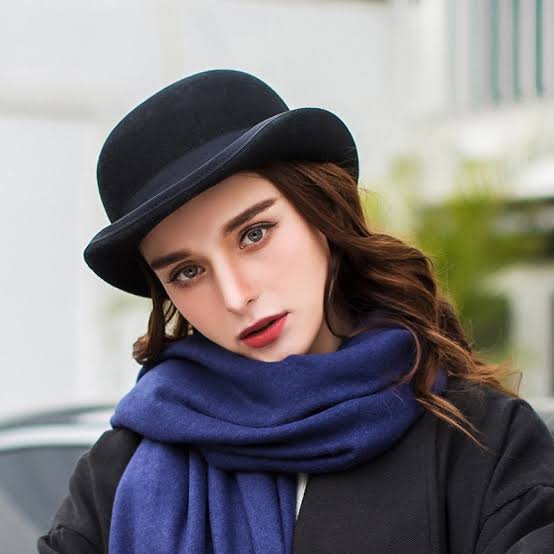A lady wearing a blue scarf and a black bowler hat