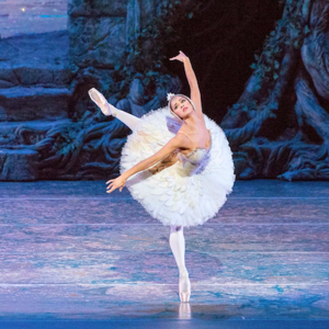 A ballerina in a white dress dancing on a stage.