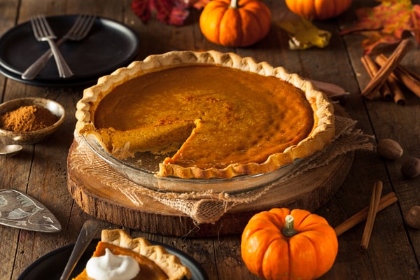 A pumpkin pie placed on a parchment paper and served on a wooden board