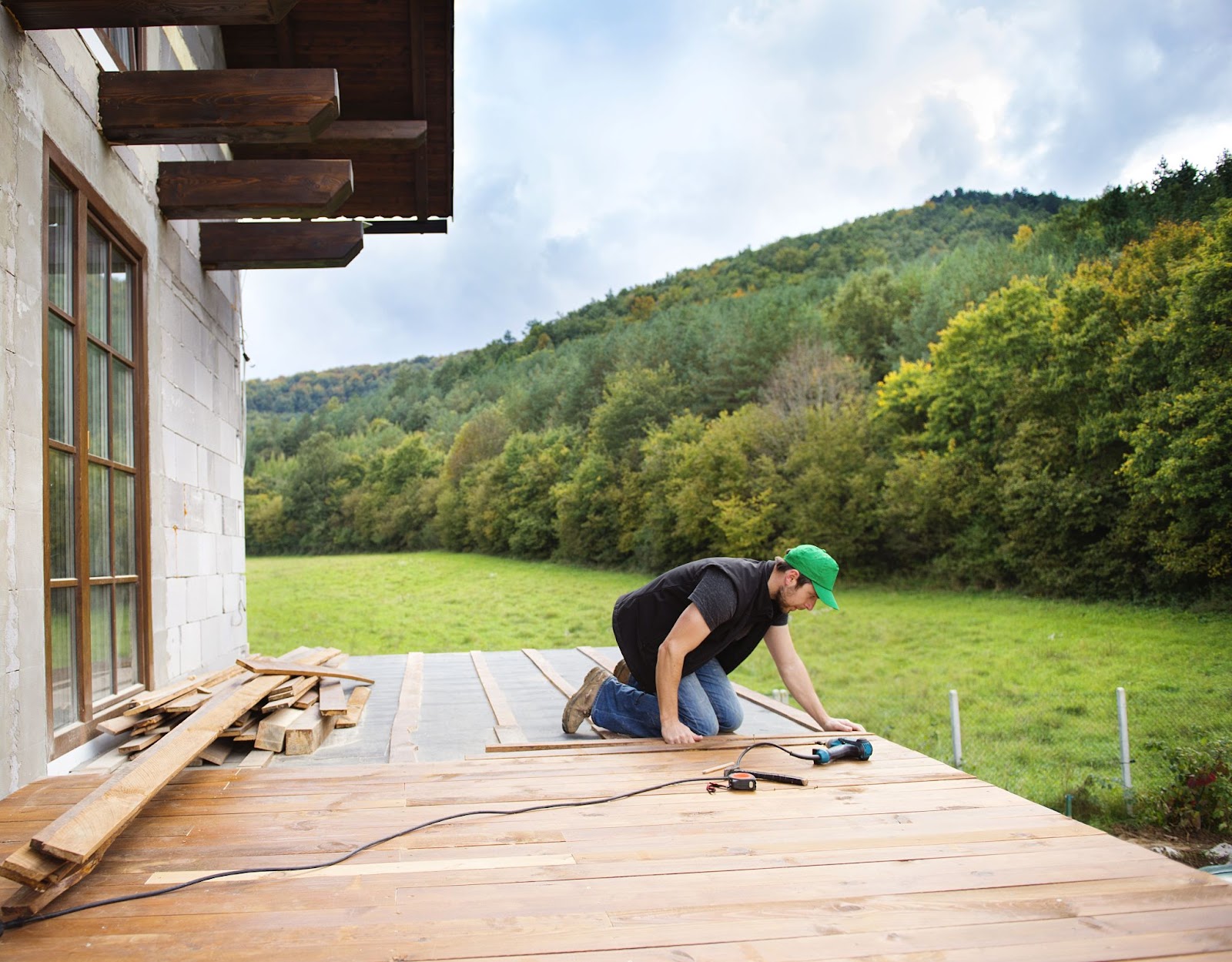 A handyman is installing wooden flooring outdoor.