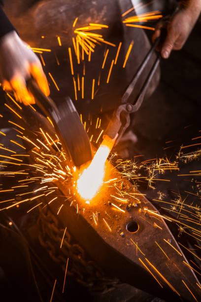 A person using a hammer to grind a metal object with sparks Description automatically generated