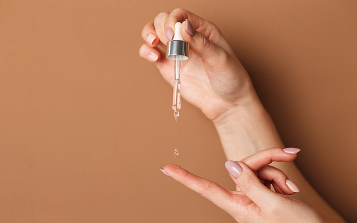 woman holding cosmetic serum pipette