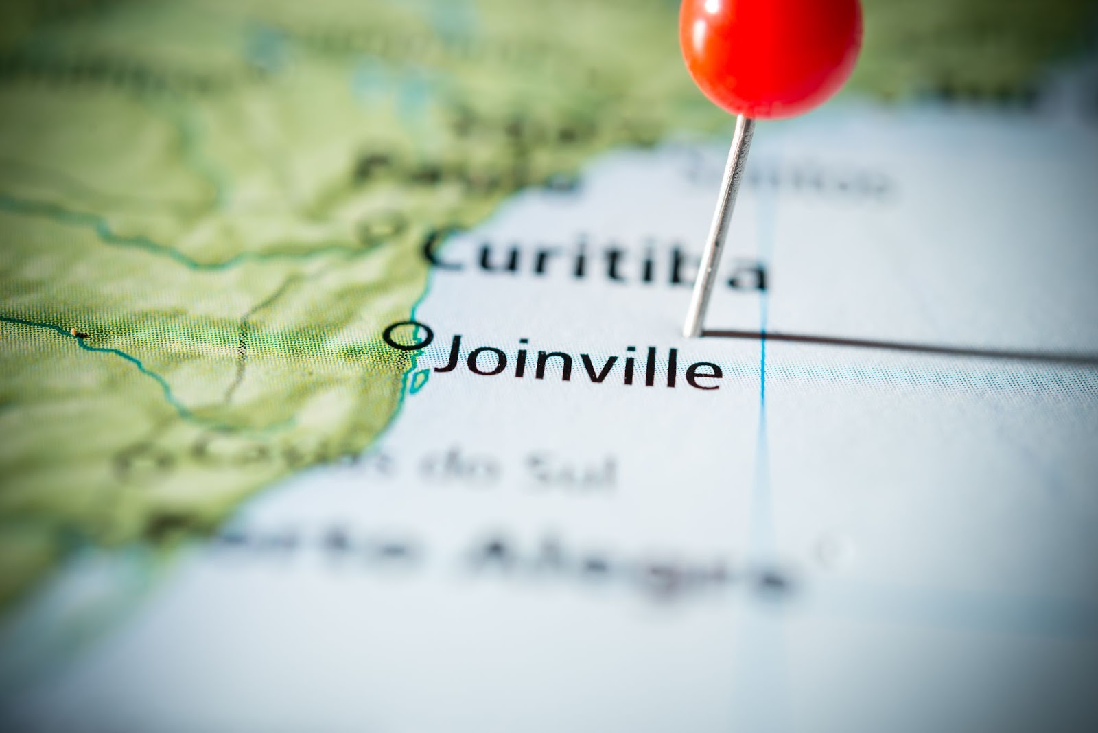 Alfinete vermelho marcando a localização de Joinville em um mapa colorido do Brasil.