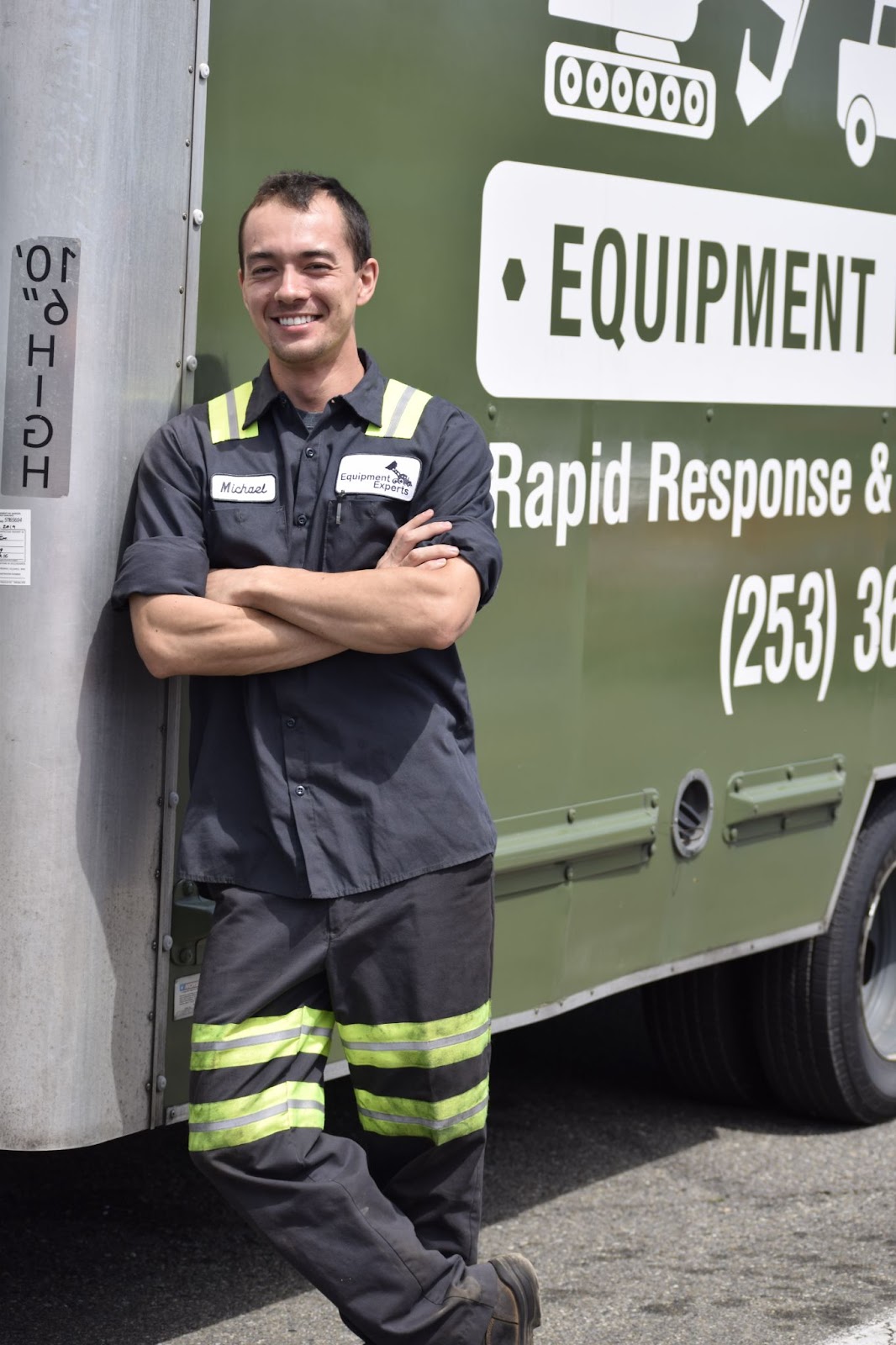 An Equipment Experts technician smiling in front of an Equipment Experts fleet vehicle