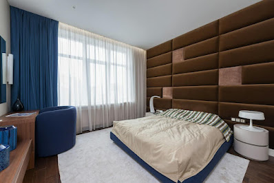 Modern bedroom with dark blue and brown furniture.