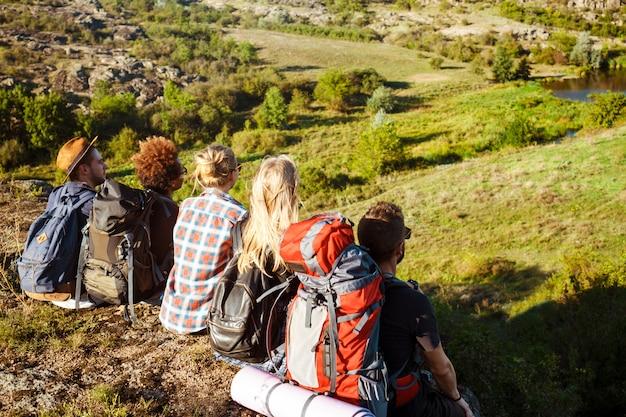 Free photo young friends travelers sitting on rock in canyon, enjoying view