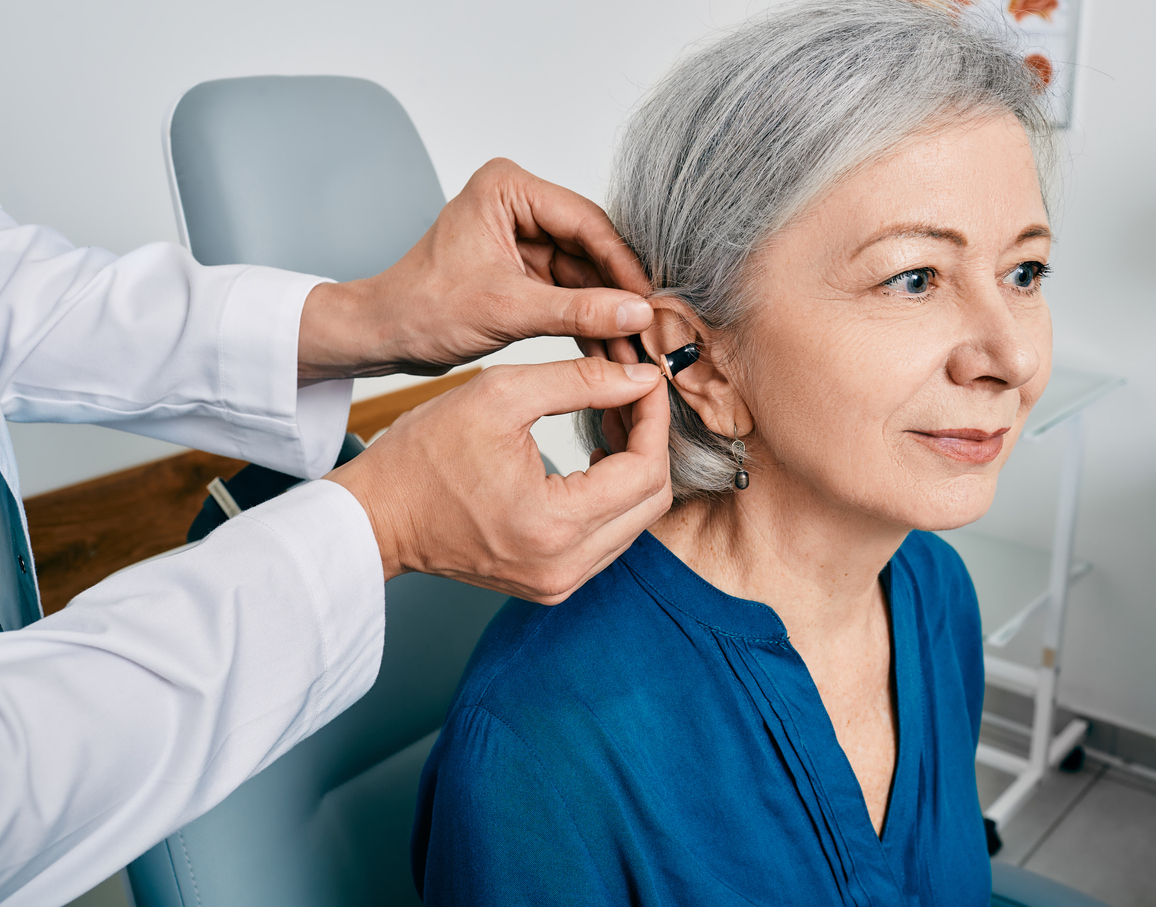 senior woman getting hearing aid fitted