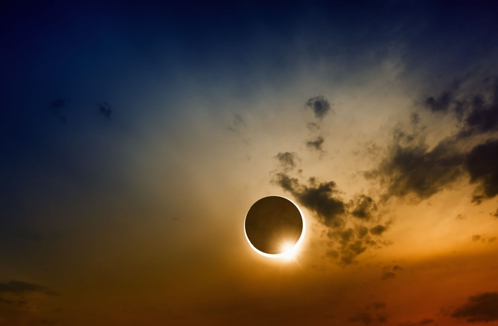 Solar eclipse at twilight with clouds in the sky.