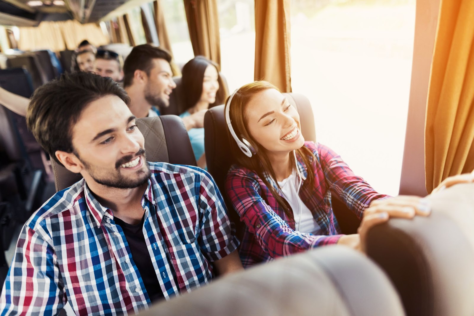 Pessoas dentro de ônibus de viagem observando a paisagem pela janela.