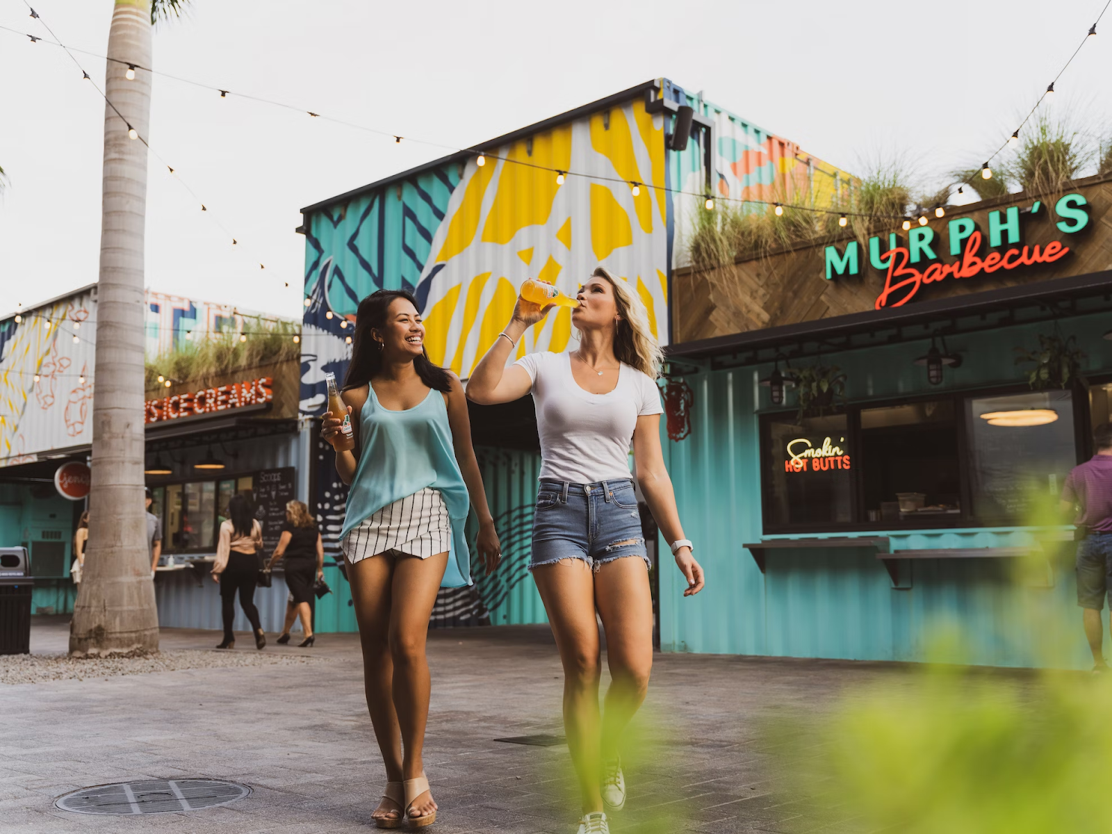 two customers walking through a downtown Florida marketplace and drinking 