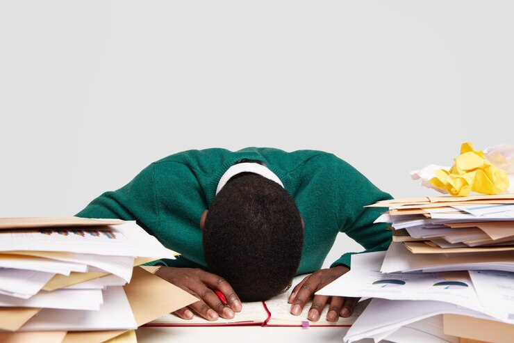 Stressed student at desk overwhelmed with preparation for A-Level English Literature exam.