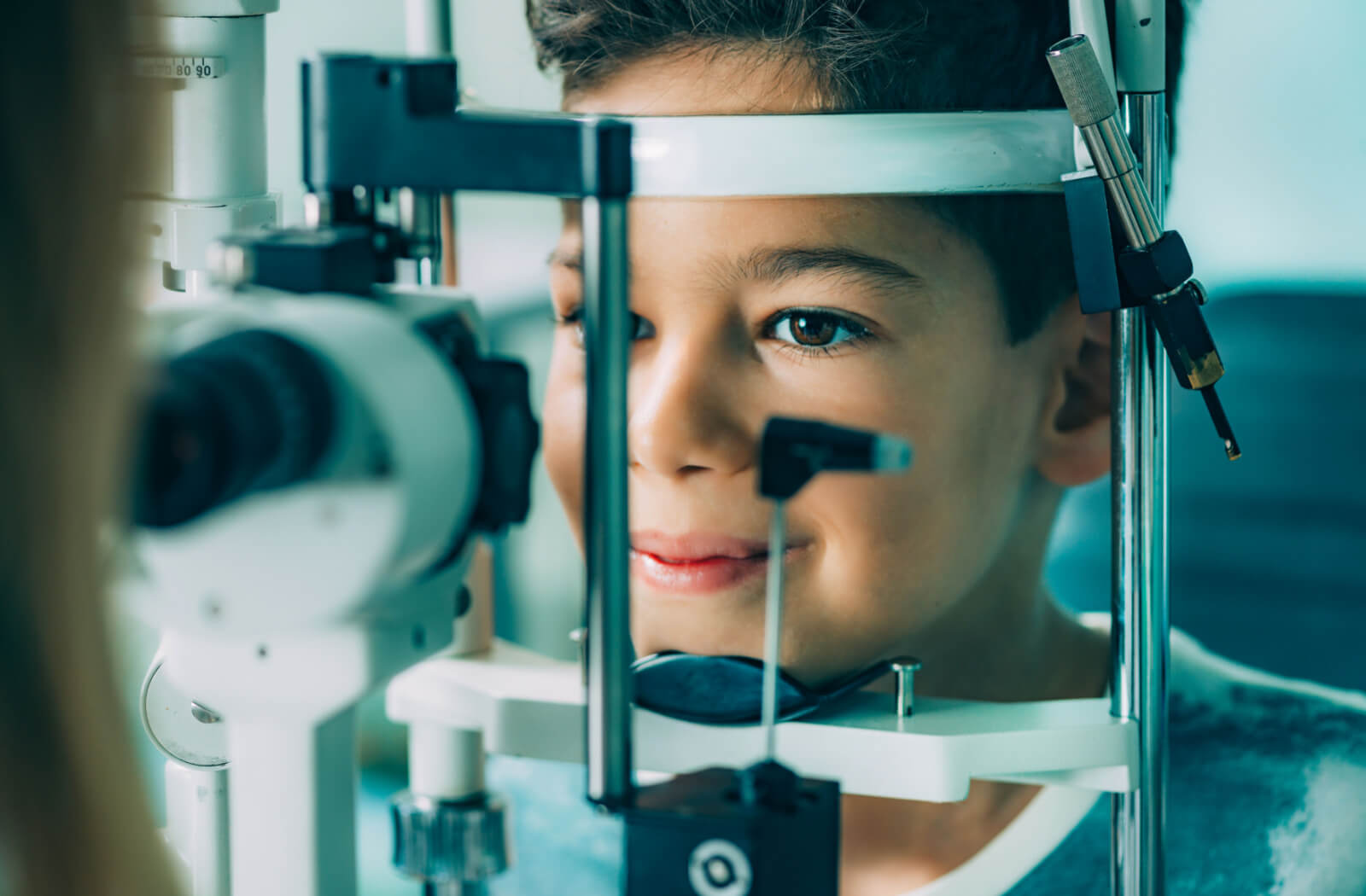 Close-up of a young boy looking into a machine that tests his vision.