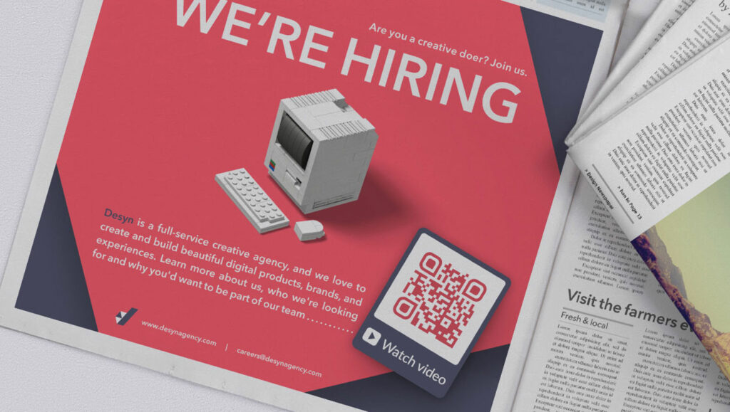 Video QR Code in a print newspaper ad prompting readers to scan and watch a video about the company