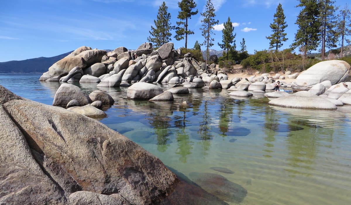 Clear waters at Sand Harbour with large rocks and trees in background