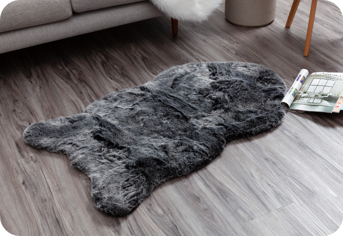 Notre tapis en fausse fourrure polaire gris foncé présenté sur un sol.