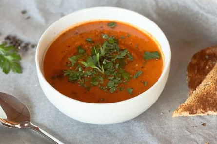 Lentil and roasted tomato soup with a side of toasted bread and herbs.