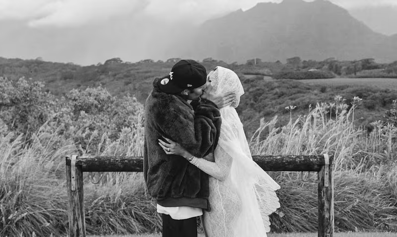 Fotografía en blanco y negro de Justin y Hailey Bieber anunciando su embarazo. La pareja se da un beso apasionado en un campo de flores.