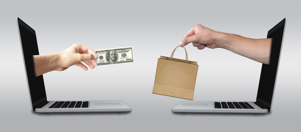 - Image showing hands emerging from 2 laptops one giving a shopping bag and another giving cash for the shopping