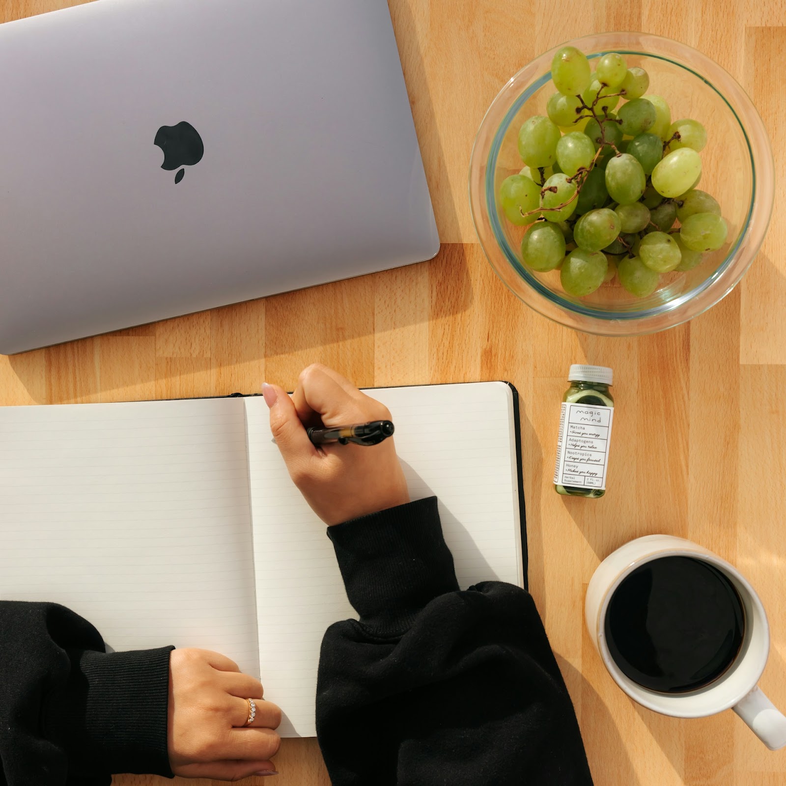 A person with a laptop and writing on a notebook