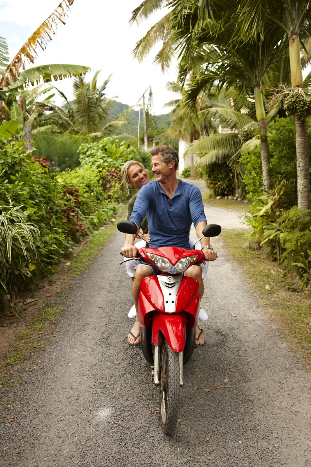 A couple riding through a lush tropical forest trail on Rarotonga.