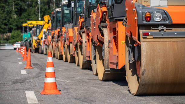 construction rollers parked at the roadside, traffic cones on the dividing line of the road - the role of asphalt paving in infrastructure development stock pictures, royalty-free photos & images