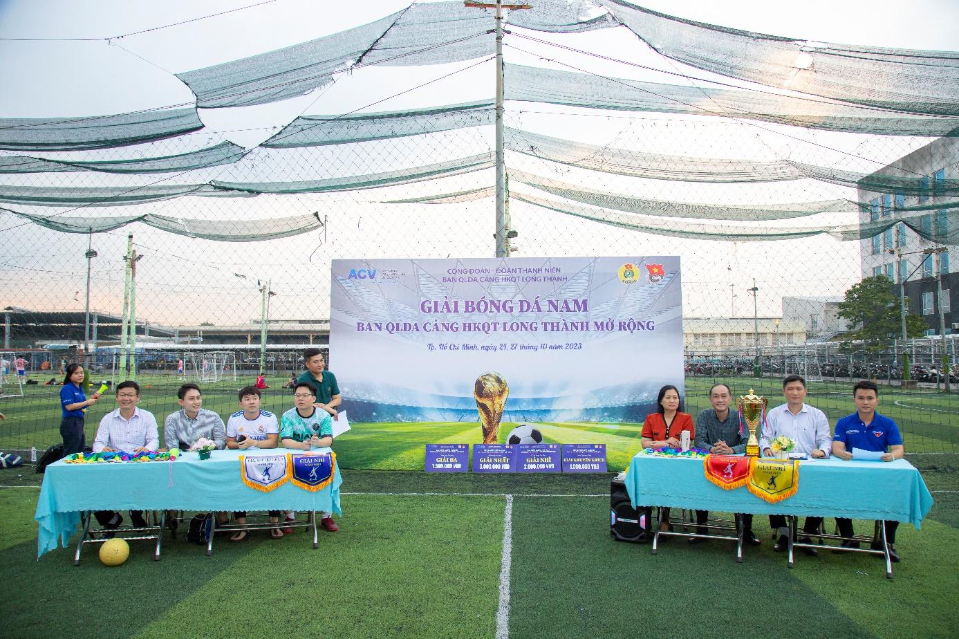 A group of people sitting at tables in front of a bannerDescription automatically generated