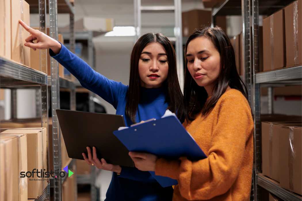 Two women with clipboards organizing boxes in a warehouse