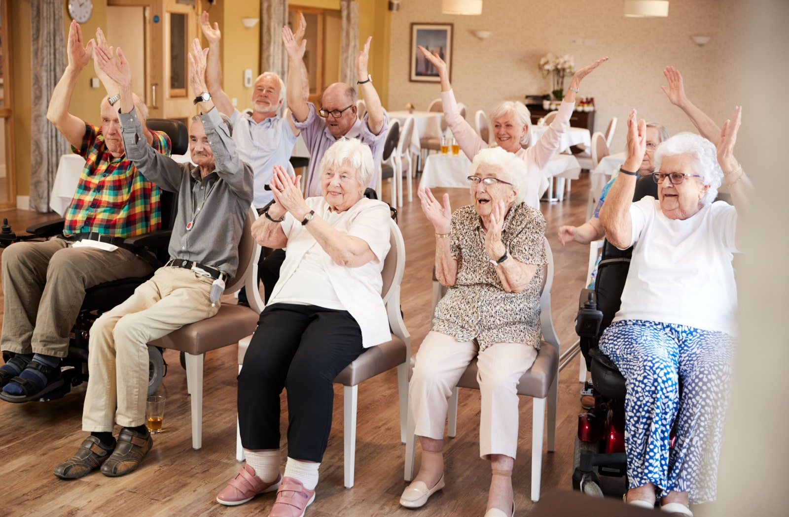 A group of senior living residents sitting in a group and performing exercises together