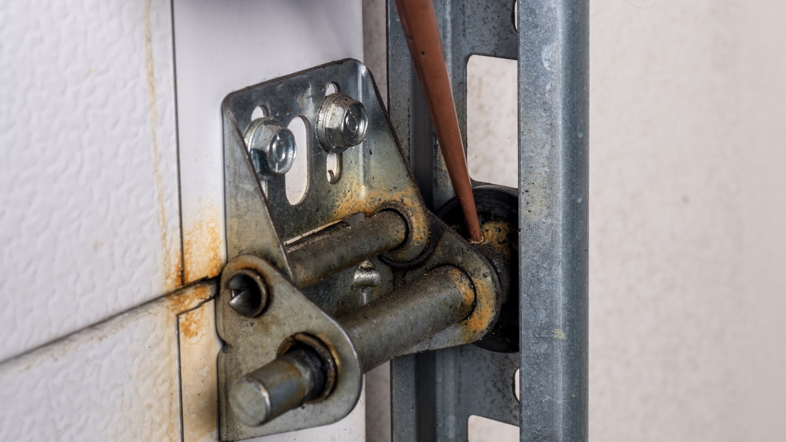 A garage door hinge being lubricated