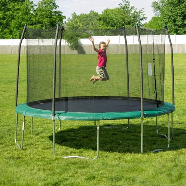 A child jumping in mid-air on a spring trampoline with green safety padding.