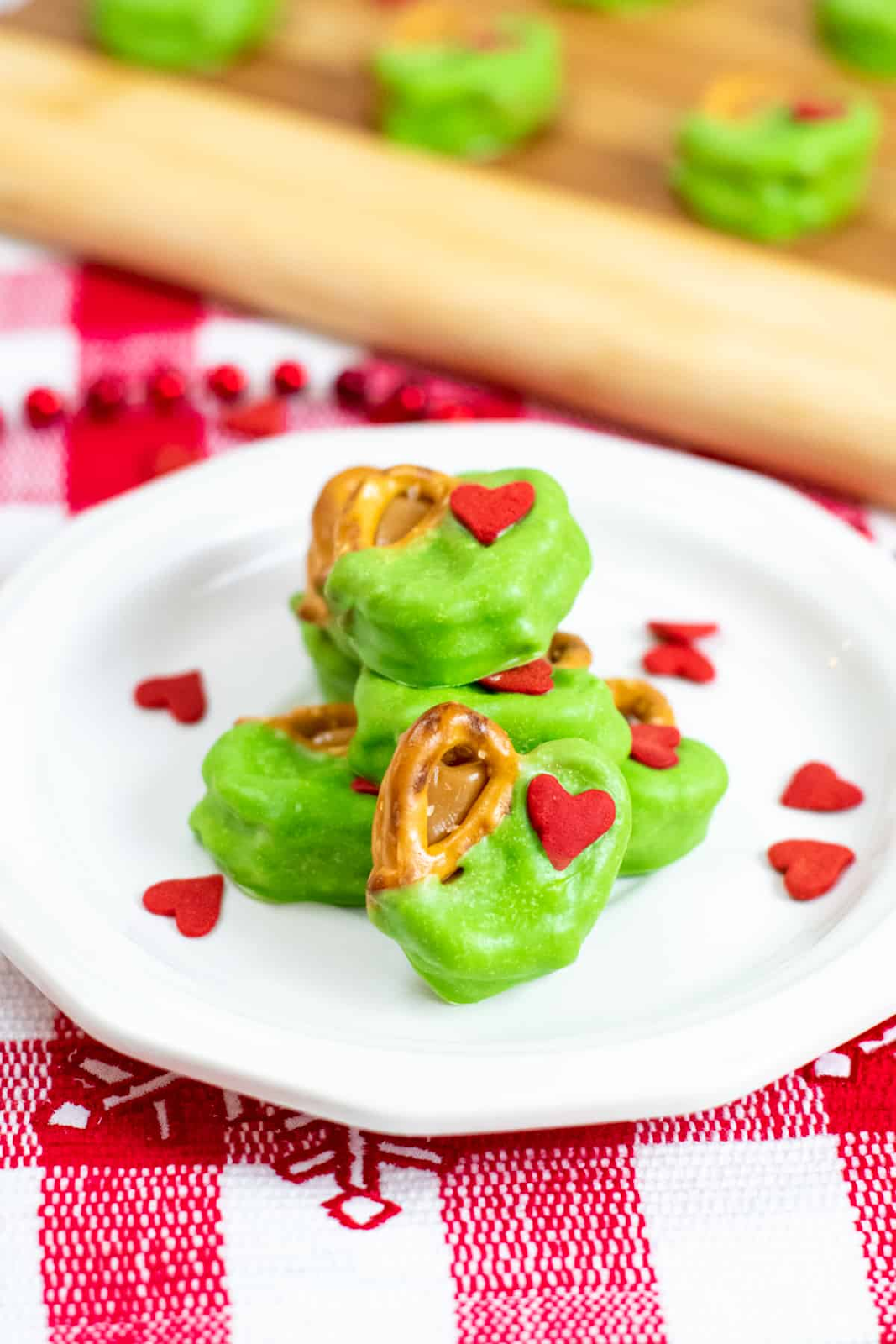 grinch pretzel bites on white plate with tiny red hearts