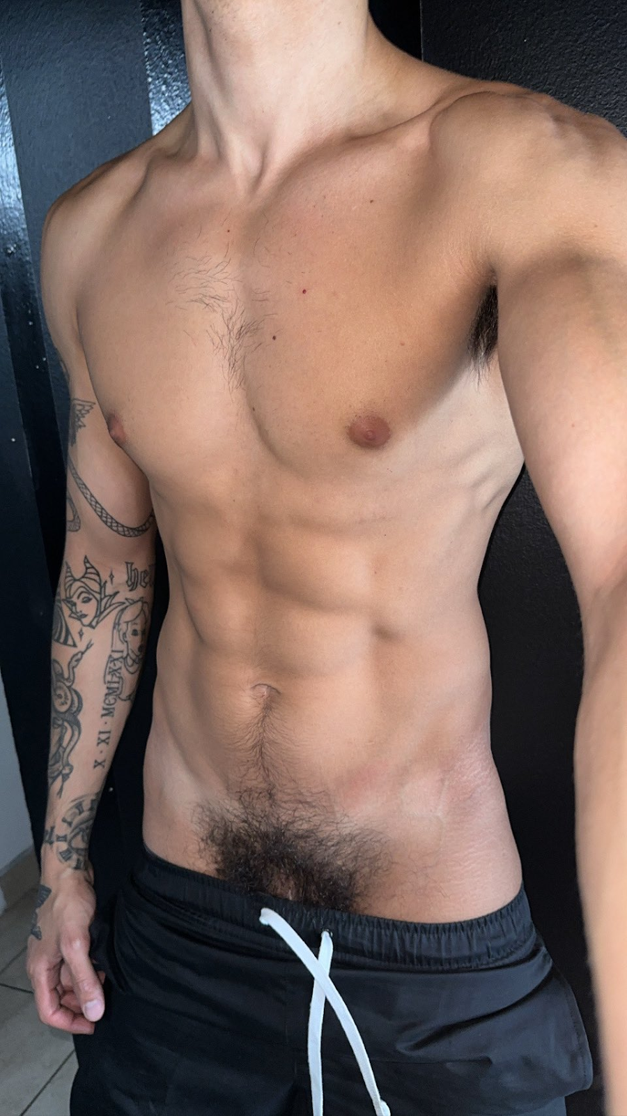 Angel Elias shirtless showing off his hairy bush and abs and arm tattoo in selfie for onlyfans gay content