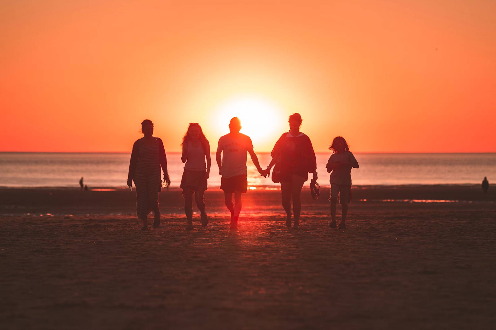 Silhouette of a family walking on the shore during sunset 