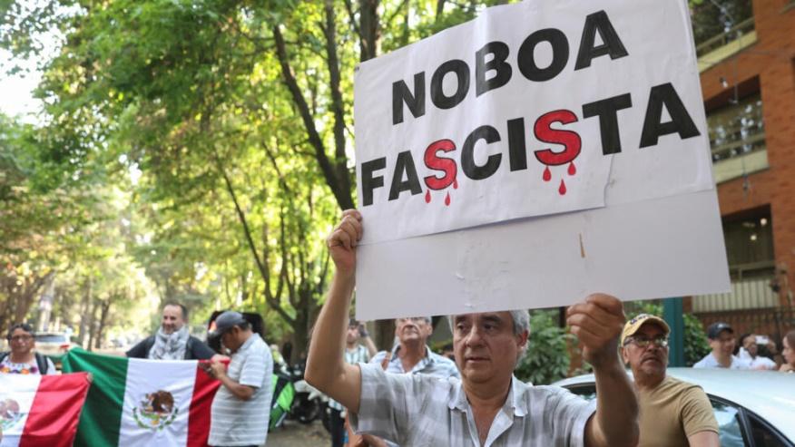 A man holds a placard that reads "Noboa Fascist" as people protest outside the Ecuadorean embassy, after Ecuadorean authorities arrested former Ecuador's Vice President Jorge Glas seizing him from the