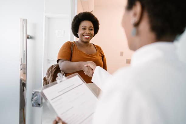 arriving at the doctor's office shake hands - black lady stock pictures, royalty-free photos & images