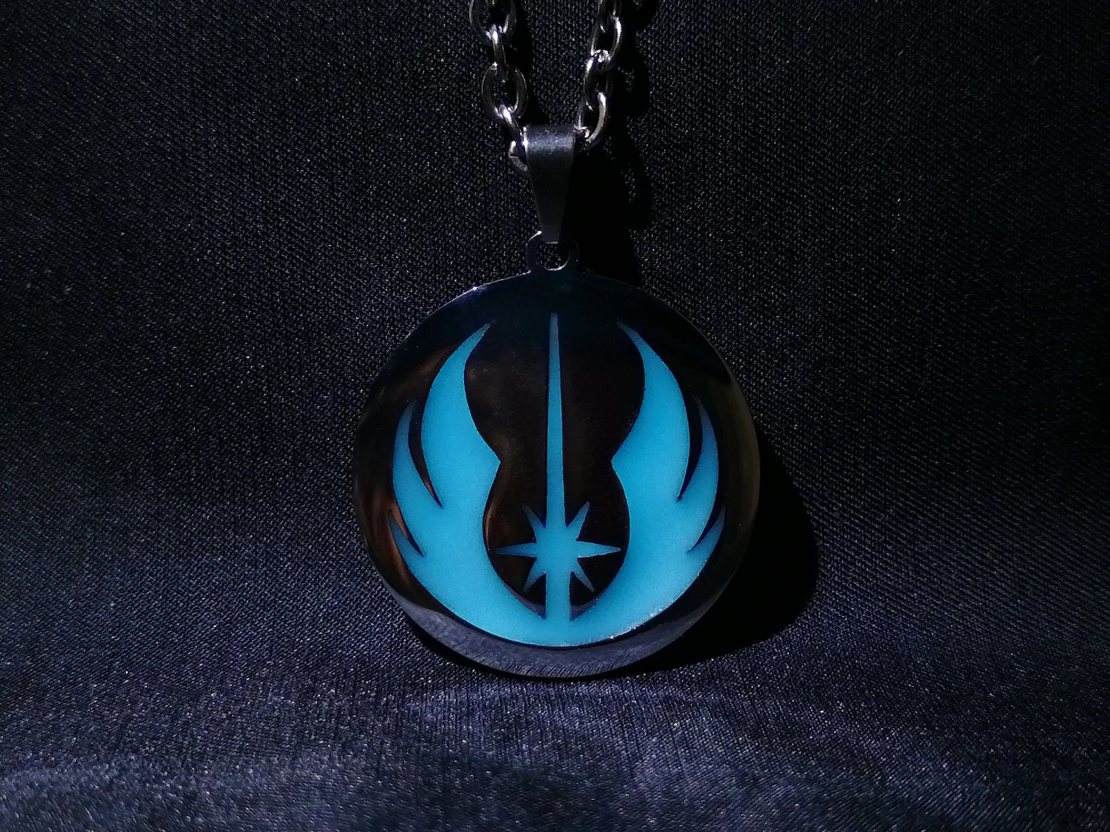 Black necklace with a blue jedi symbol on the charm